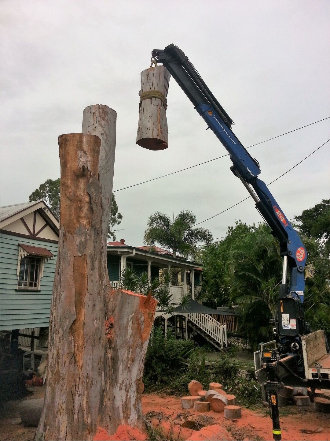 Crane truck lifting a trunk section clear of a Queenslander