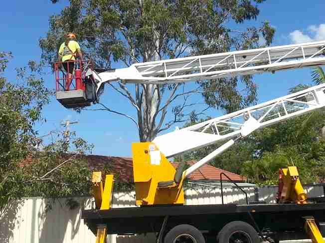 Truck-mounted elevated work platform with a crew member in the basket beside a house roof