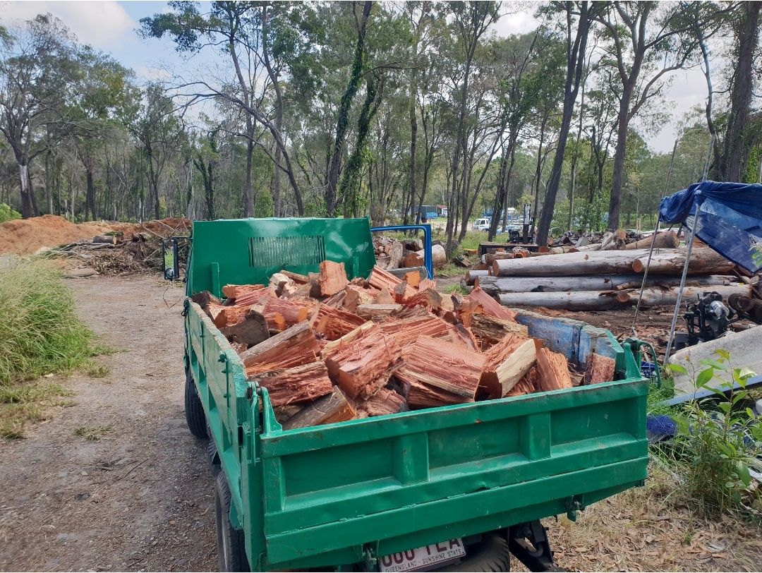 Green tipper trailer loaded with split firewood